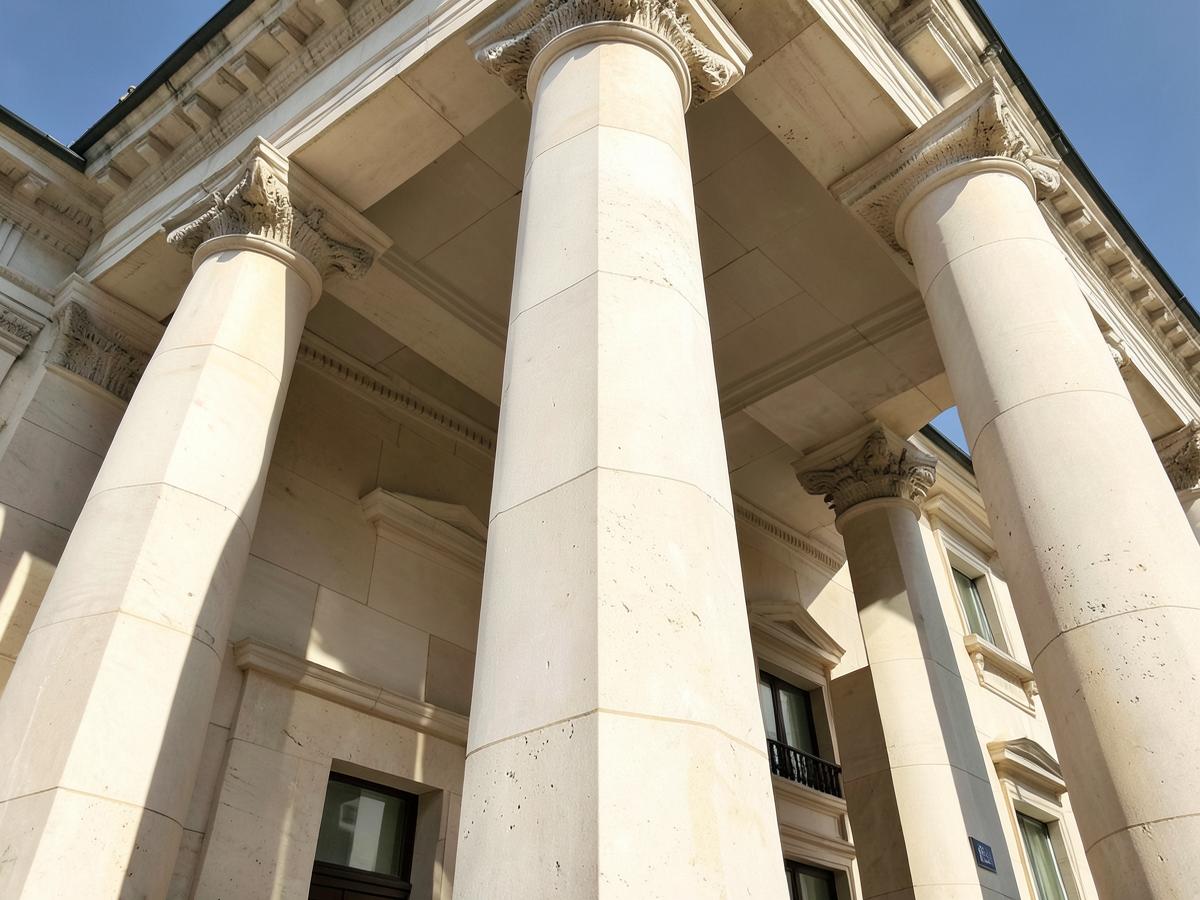 Stone columns of a neoclassical city hall photographed from below against a clear sky
